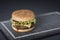 Hamburger with a double serving of meat, tomatoes, salad, onions on a wooden board in a restaurant.Copy space