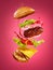 The hamburger with flying ingredients on rose background