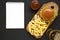 Hamburger with lettuce, cheese and bacon on a rustic wooden board on a black background, top view. Blank notepad