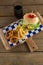 Hamburger, onion ring and french fries with cold drink on chopping board