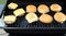 Hamburger patties with processed cheese slices cooking on an outdoor table top barbecue