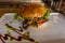 Hamburger in the white plate on a table. Rustic closeup.