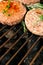 hamburgers and hot dogs with rosemary cooking on grill