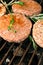 hamburgers and hot dogs with rosemary cooking on grill