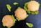 Hamburgers with juicy cutlet, green lettuce leaves and a soft bun with sesame on the black background