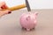 Hammer aiming for pink piggy bank money box on light background. Piggy bank  on wooden background, space for text. Finance, saving