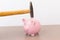 Hammer aiming for pink piggy bank money box on light background. Piggy bank  on wooden background, space for text. Finance, saving