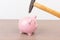 Hammer aiming for pink piggy bank money box on light background. Piggy bank  on wooden background, space for text. Finance, saving