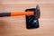 A hammer hits the broken smartphone on the screen. On a wooden background.