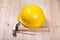 Hammer, pencil and yellow hardhat on wood background