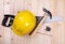 Hammer, pencil and yellow hardhat on wood background