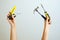 Hammer, screwdriver, pliers, paper knife in female hands over head. Construction tools on outstretched arms