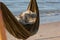 Hammock on the beach at sunset with glowing bokeh from blue sea. Green hammock with a hat and shoes, slates.