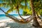 hammock swaying gently between two palm trees, overlooking a pristine white sandy beach