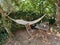 Hammock, table and wooden chairs in rustic garden. Patio in nature. Concept of rest and relaxed atmosphere. Garden furniture and