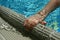 Hand of 5 years old boy holding edge of swimming pool