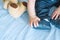 The hand of a 6-month-old baby touches his booties, next to which is a toy bear. Child development concept