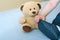 The hand of a 6-month-old baby touches his booties, next to which is a toy bear. Child development concept