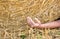 The hand of an accidental farmer under a big straw bale