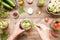 Hand adds canning ingredients to the jar and other canning vegetables on wooden background. Food preservation and conservation