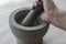 The hand of an adult Caucasian man grinds random medicinal roots and herbs in stone mortar