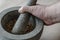 The hand of an adult Caucasian man grinds random medicinal roots and herbs in stone mortar