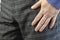 Hand Adult Man in gray plaid trousers and blue shirt close-up