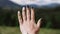 Hand against mountain. Female hand forward. Mountain valley