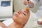 Hand applying facial mask with orange brush in spa treatment alternative medicine