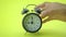 Hand asian male picking black alarm clock place on yellow table indoor studio shot isolated on yellow background