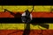 Hand assault rifle on the background  flag of Uganda and cracks. Uganda Power Concept