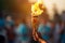 A hand of athlete holds the cup with an torch against a blurred colorful background. Olympic torch