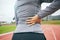 Hand, back pain and fitness with a sports person outdoor on a track suffering from injury or discomfort. Exercise