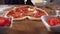 of hand of baker chef making heart shaped pizza in kitchen. The chef sprinkles the pizza with cheese, a lot of cheese on