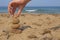 A hand balances ocean balls of posidonia seaweed on the beach.