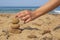 A hand balances ocean balls of posidonia seaweed on the beach.