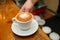 Hand barista holding and serving cup of coffee.