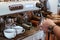 Hand barista steam milk in metal mug on coffee maker