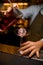 hand of barman holds strainer and mixing cup with beverage and pour it into wine glass with ice