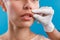 Hand of beautician touching female lips, examining face before giving botox injection