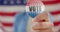 Hand of biracial teenage girl agaisnt american flag holding vote badge, slow motion
