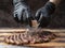 Hand in black glove scratch Himalayan stone salt to sliced beef steak on wooden cutting board.