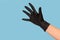 A hand in a black glove shows front five on a blue background. Hygiene, tattoo master