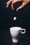 Hand of black man drop piece of sugar in white cup
