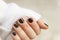 hand with black manicure on short nails in a white sweater on a light background. The concept of a stylish and warm winter