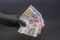 A hand in a black medical glove holds a wad of euros on a dark background, selective focus, close-up. Concept: cash payment during