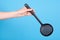 Hand with black plastick ladle utensil. Isolated on blue background