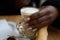 Hand of a black woman with false nails holding a cup of coffee with milk