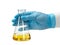 Hand in a blue glove holding a glass chemical vessel for experiments