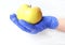 A hand in a blue glove holds a green Apple on a light background, side view, close - up-the concept of eating pure fruit